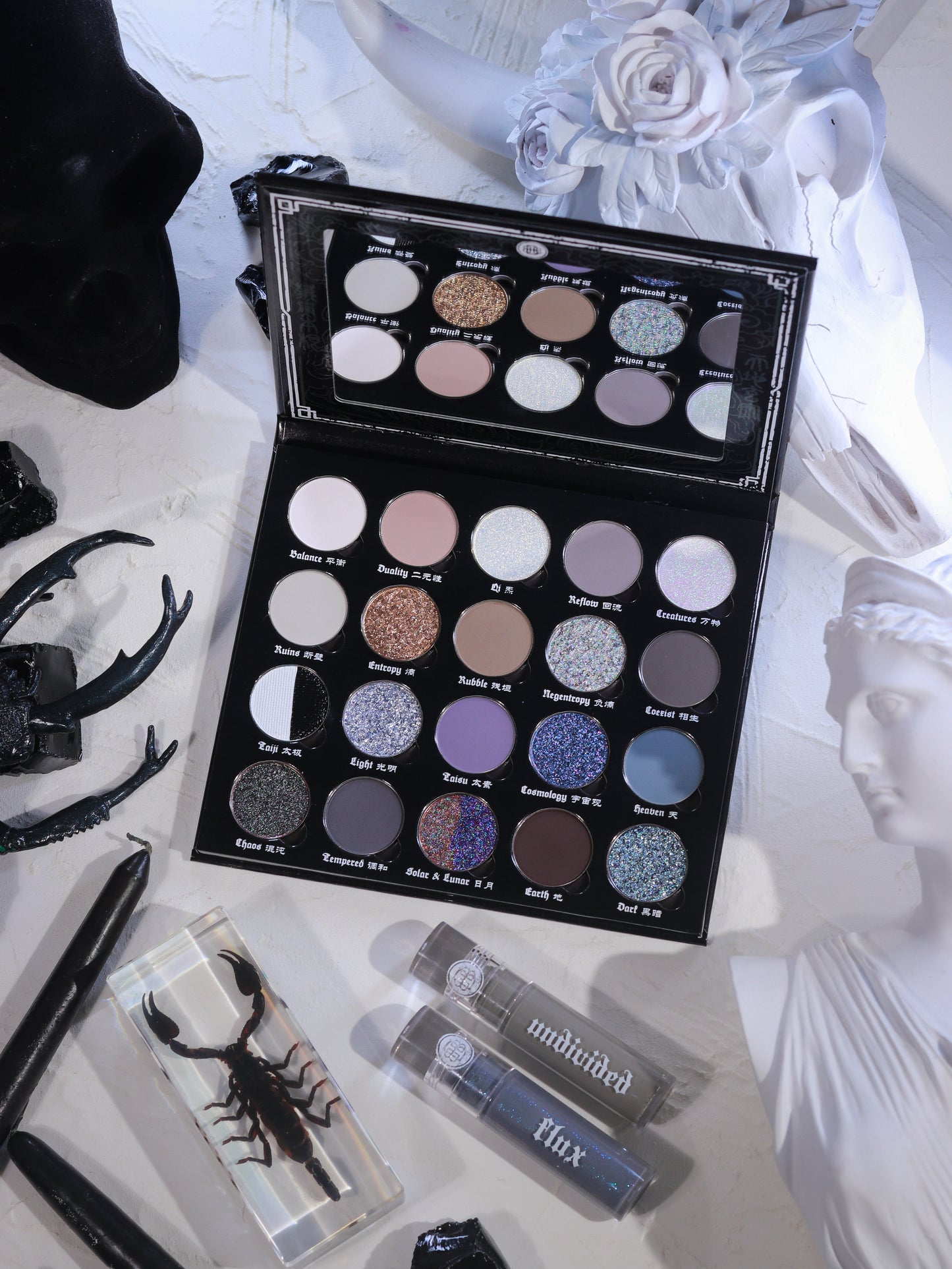 BellaBeauteBar Yin & Yang x Freya86_ff eyeshadow palette open with Flux and Undivided liquid eyeshadows, surrounded by black antlers, preserved scorpion, and white floral statuary