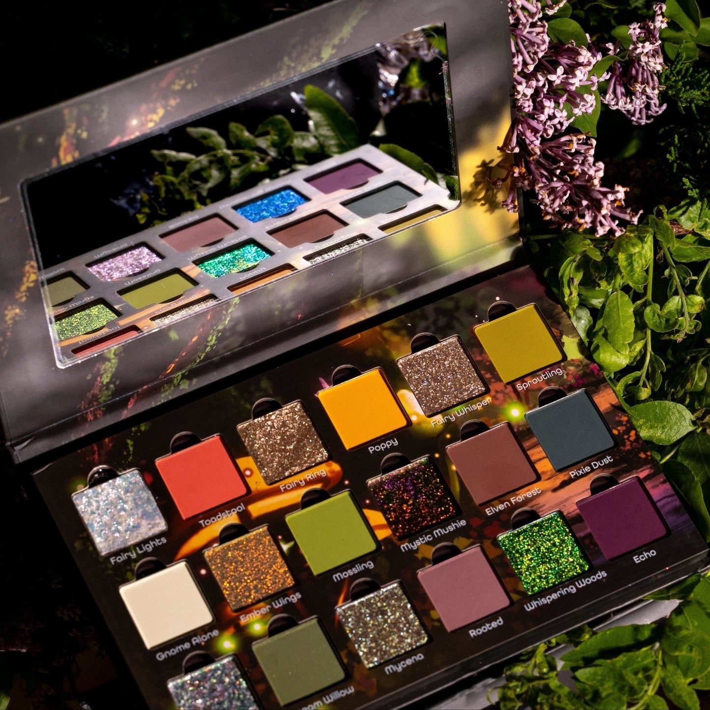 Whispering Woods palette open in a night garden with pink flowers, lid reflected in the palette mirror, all three rows visible