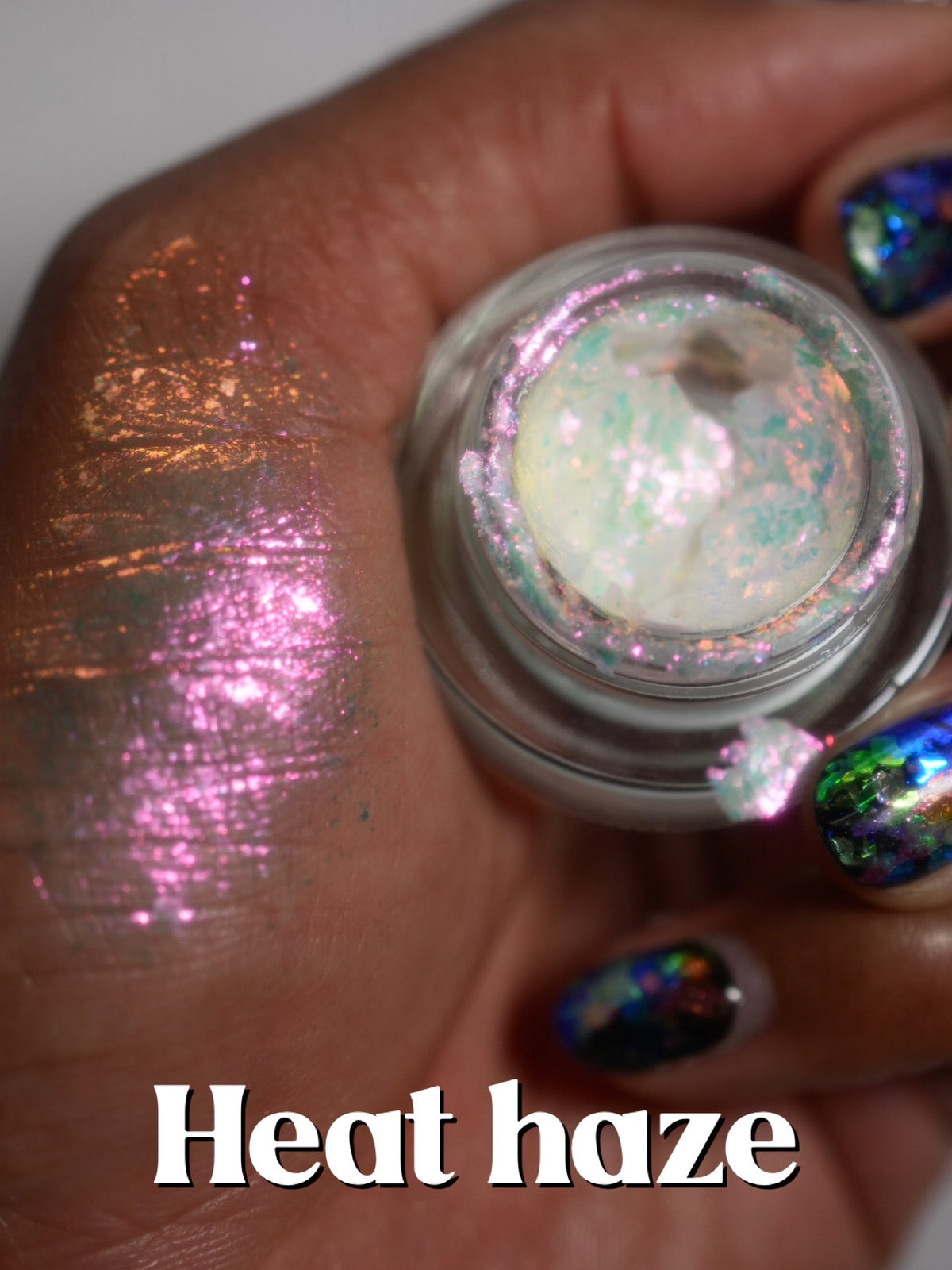 Heat Haze jar held up with a second finger swatch on deep skin