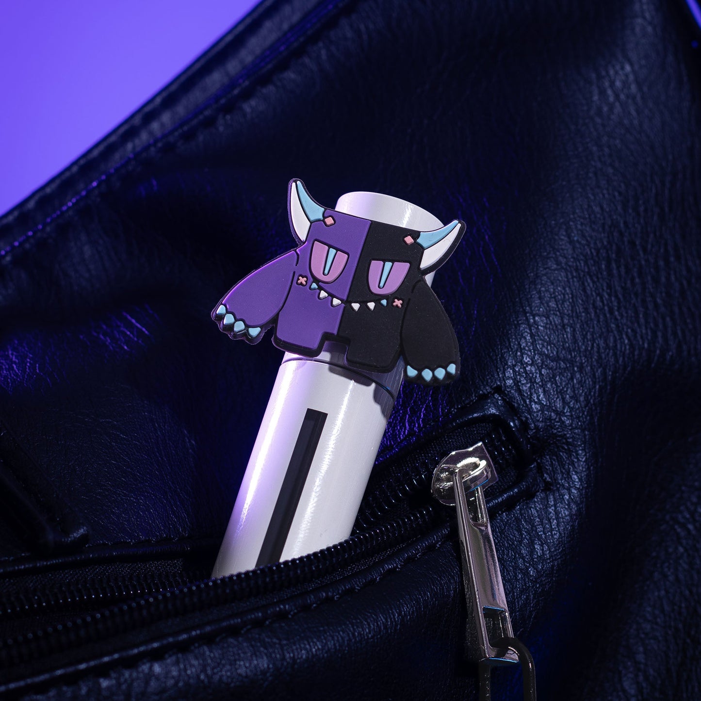 Spite lip milk tube with its Gloom mascot topper tucked into the pocket of a black bag.