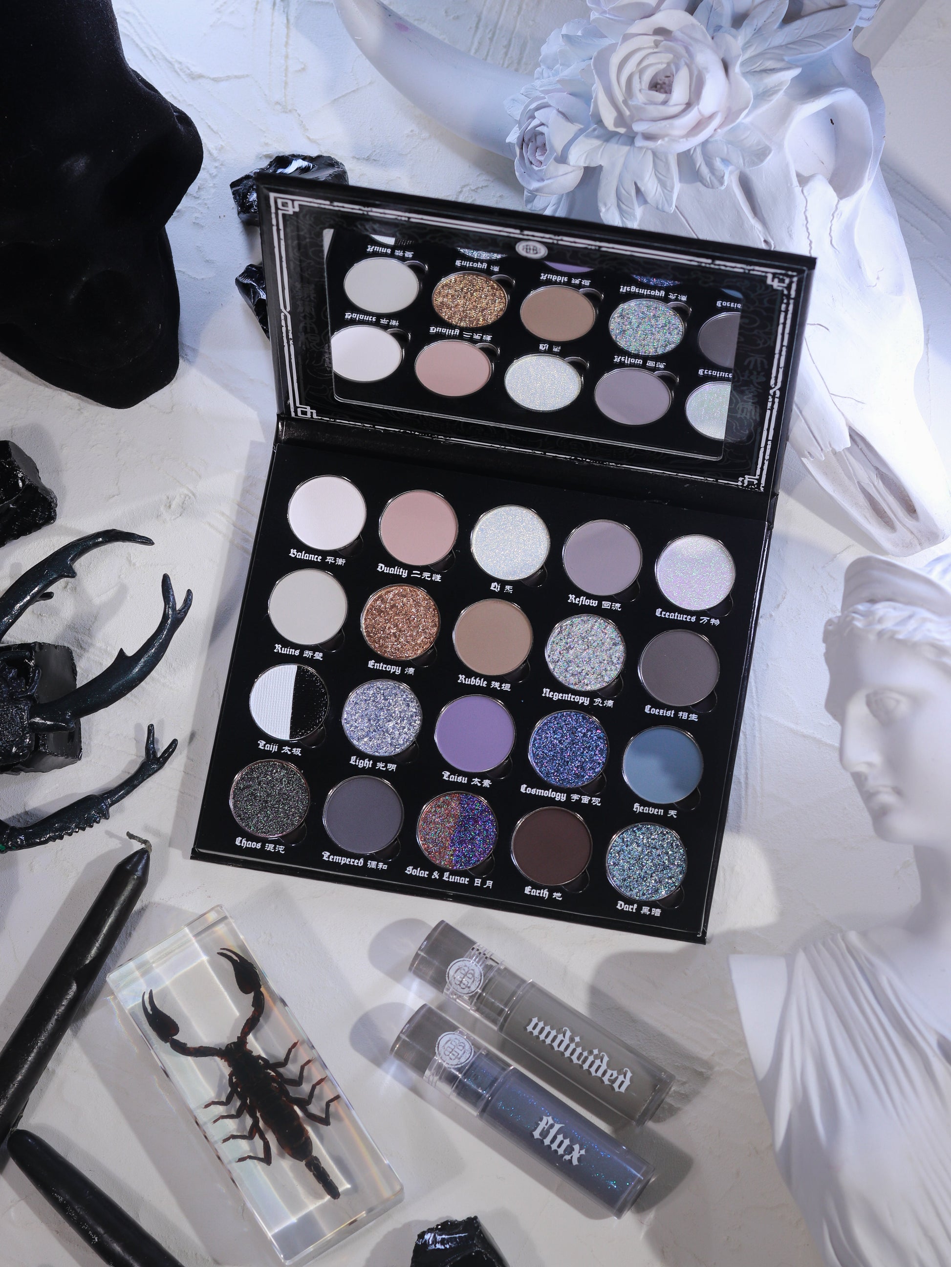 BellaBeauteBar Yin & Yang x Freya86_ff eyeshadow palette open with Flux and Undivided liquid eyeshadows, surrounded by black antlers, preserved scorpion, and white floral statuary