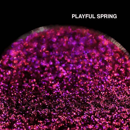 Macro of Playful Spring pressed pan, magenta pink multichrome with violet flash, shade name in white type top right.