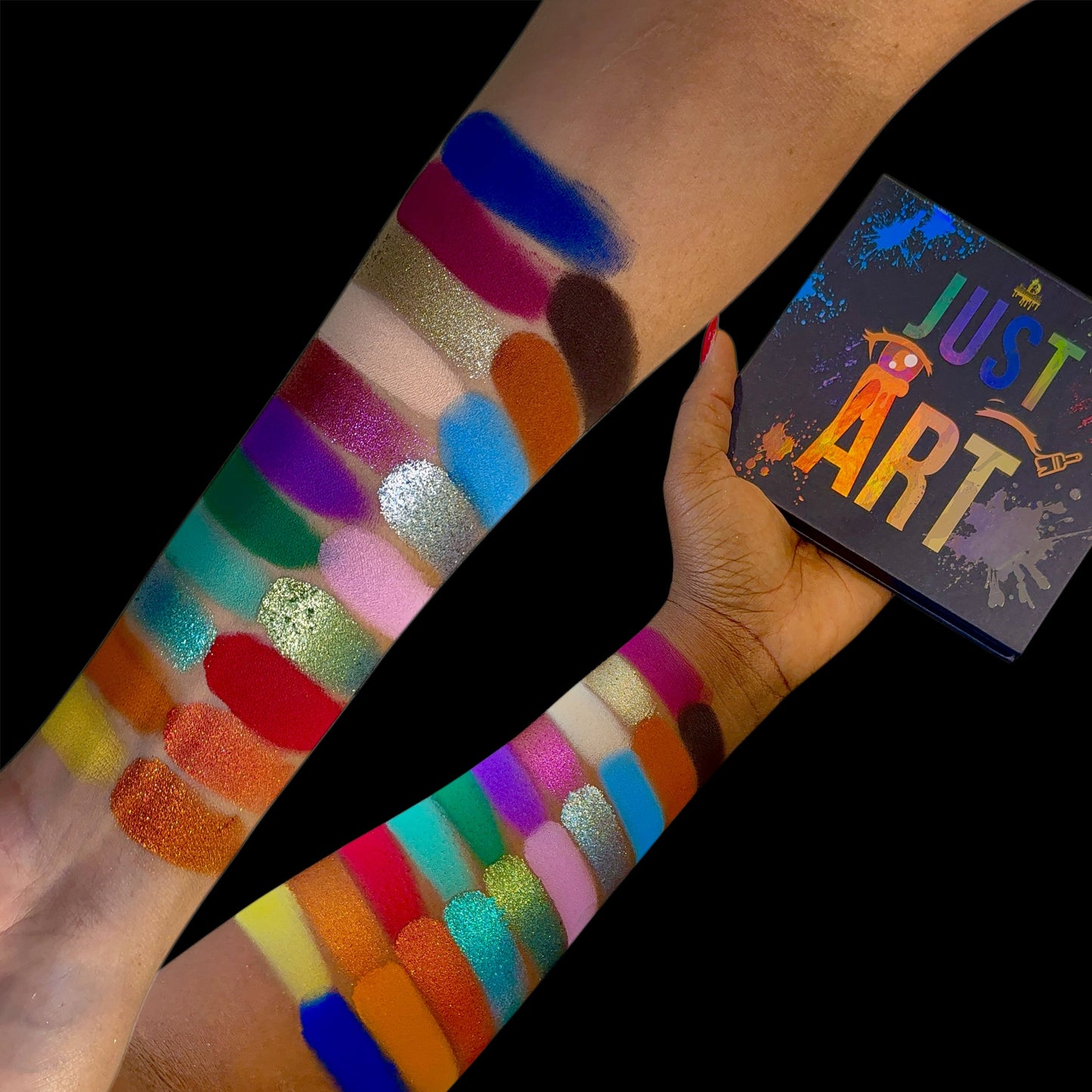 Arm swatches of the Just Art shades on two skin tones against black, the Just Art box held alongside