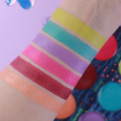 Unlabelled arm swatches on light skin beside the open palette, on a lilac background.
