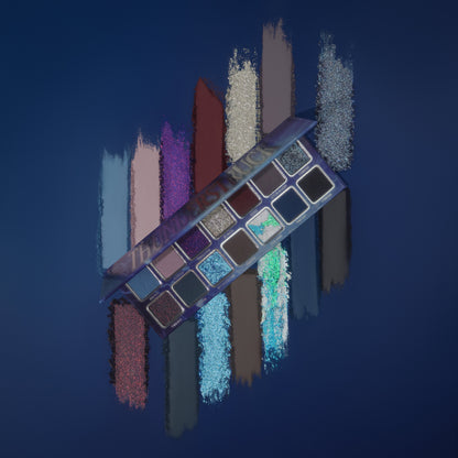 Thunderstruck palette tilted over powder swatch streaks on a deep blue backdrop, slate blues, mauves, violet and silver sparkles, a dark red and browns