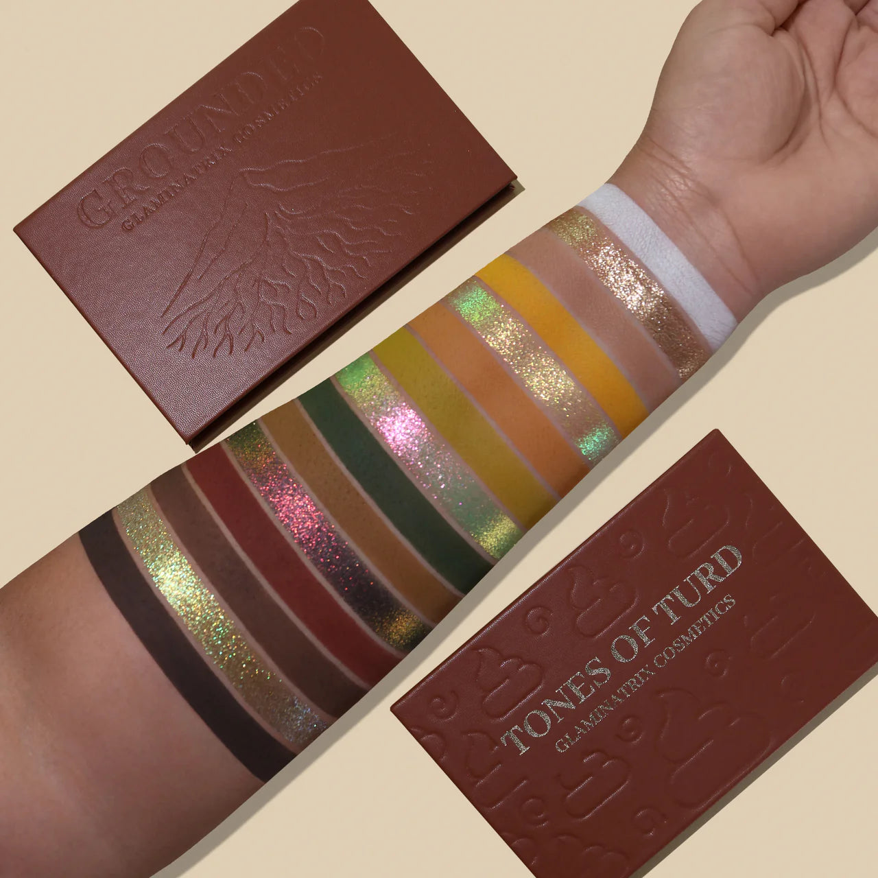 Full shade range swatched on a medium skin tone beside the closed Tones of Turd and Grounded palettes, green-pink multichromes, gold shimmer, and warm mattes