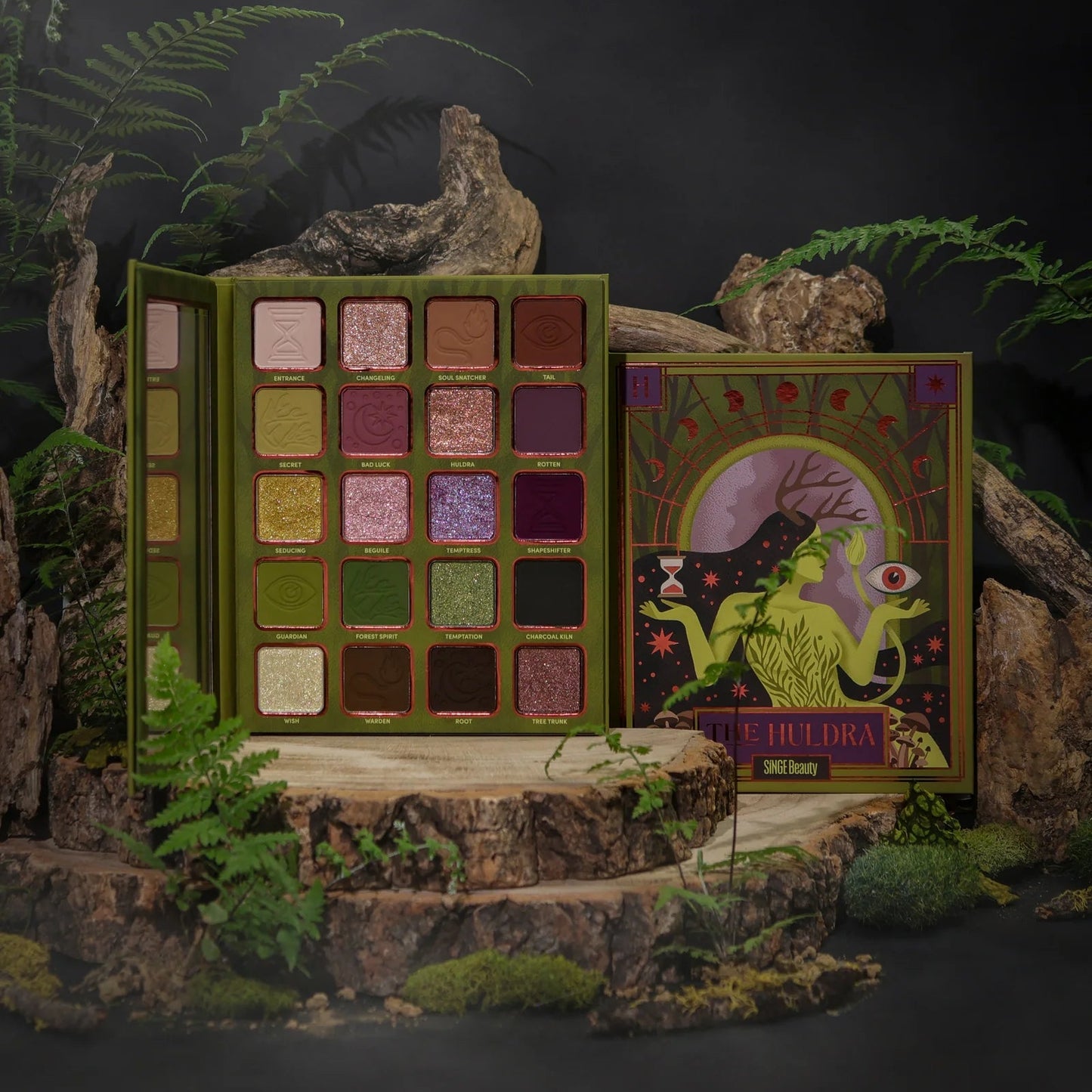The Huldra palette open on a mossy log with ferns, beside its closed box illustrated with an antlered green forest spirit holding an hourglass