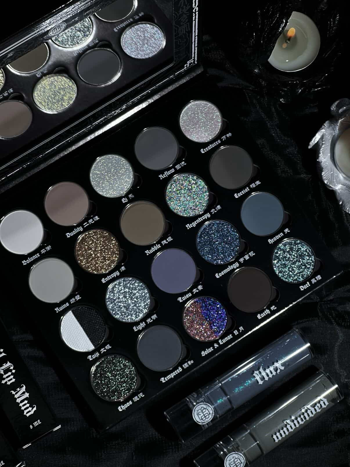 BellaBeauteBar Yin & Yang x Freya86_ff eyeshadow palette flat lay with Flux and Undivided liquid eyeshadows and candle, showing all 20 shades in moody candlelit setting