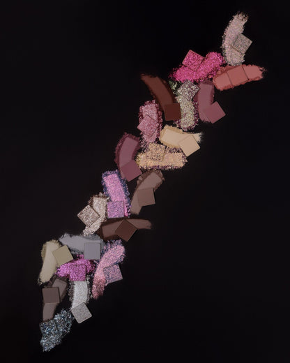 Cold Moon palette - individual pans and swatches scattered diagonally on black background, showing the full colour range from teal sparkles to warm pinks