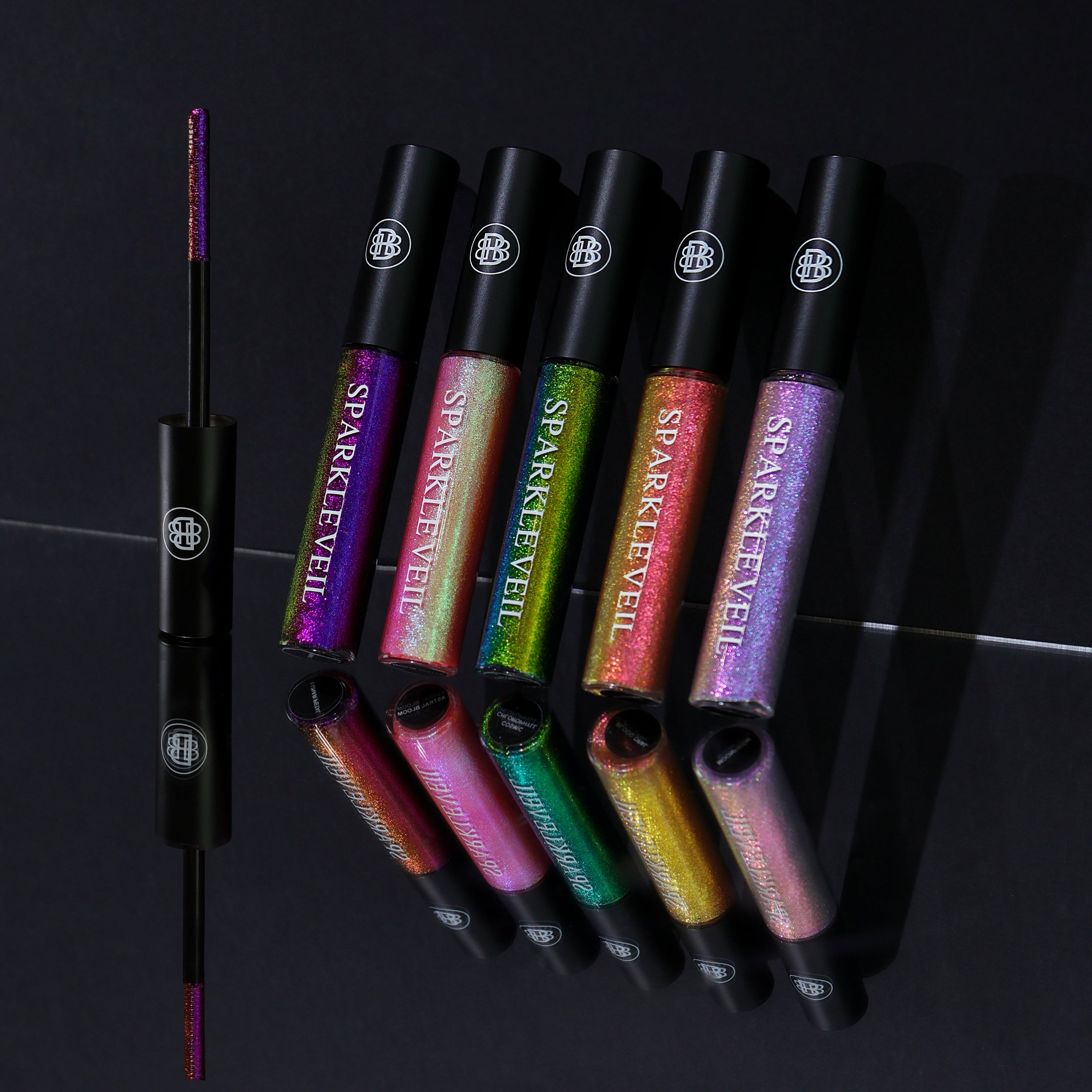 All five Sparkle Veil mascara topper tubes standing with mirror reflection