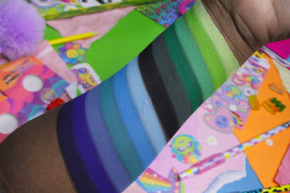 Close-up of green, blue, and indigo stripe swatches on deep skin over a colourful 90s sticker collage