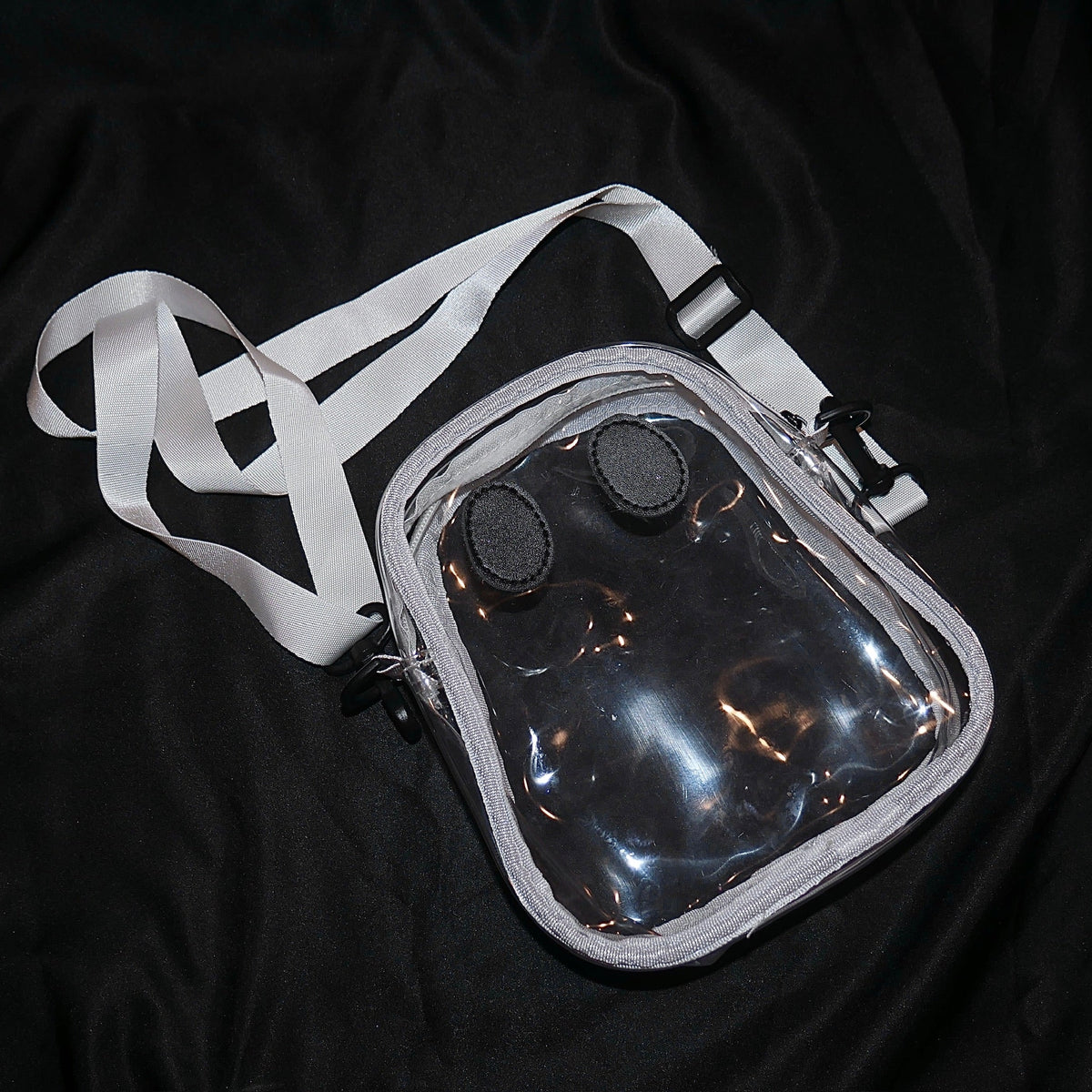 The clear Ghostie bag laid flat with its adjustable strap unclipped, showing the ghost shape and the two sewn-on eyes