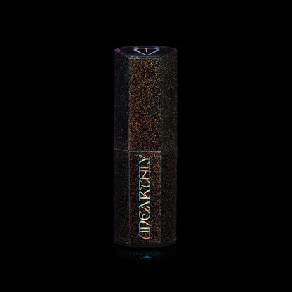 Closed Menacing Cream lipstick in a black hexagonal tube with multicoloured sparkle flecks and an iridescent Unearthly logo