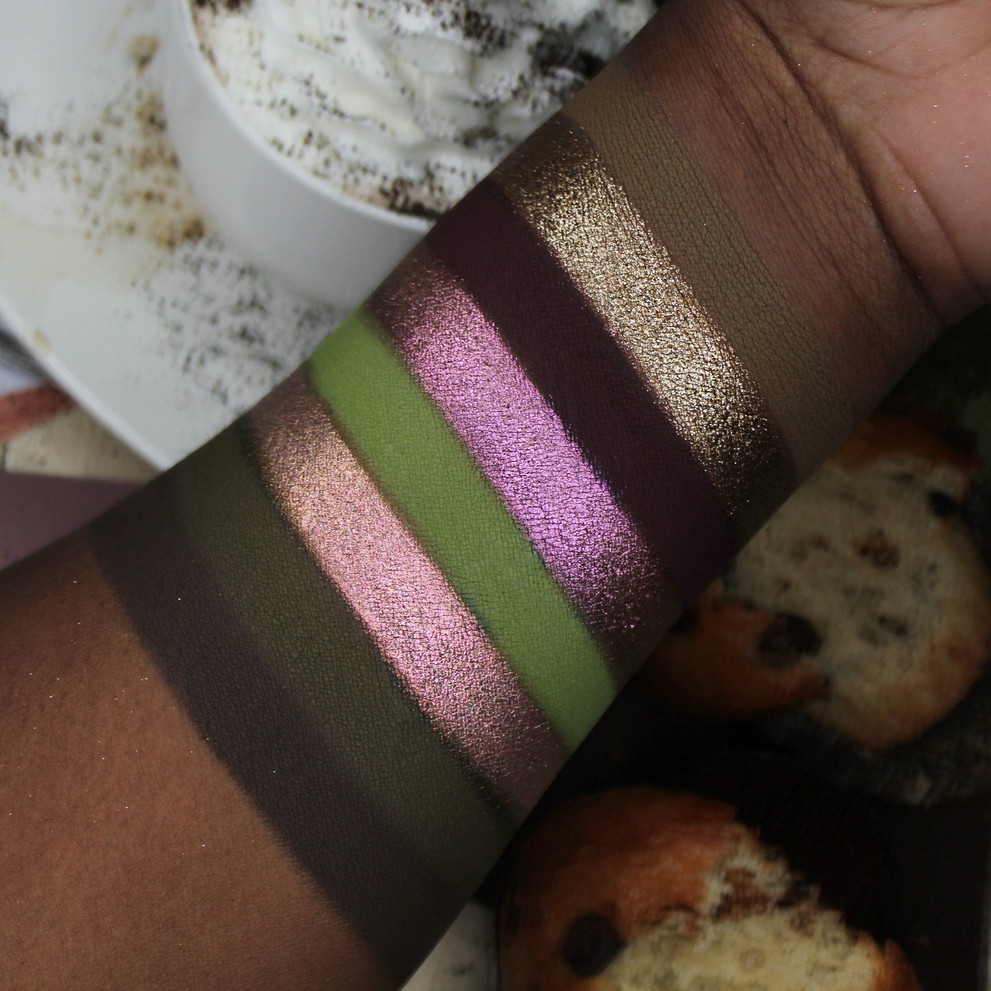 Color swatch with glittery shades held over a blurred background of food items.