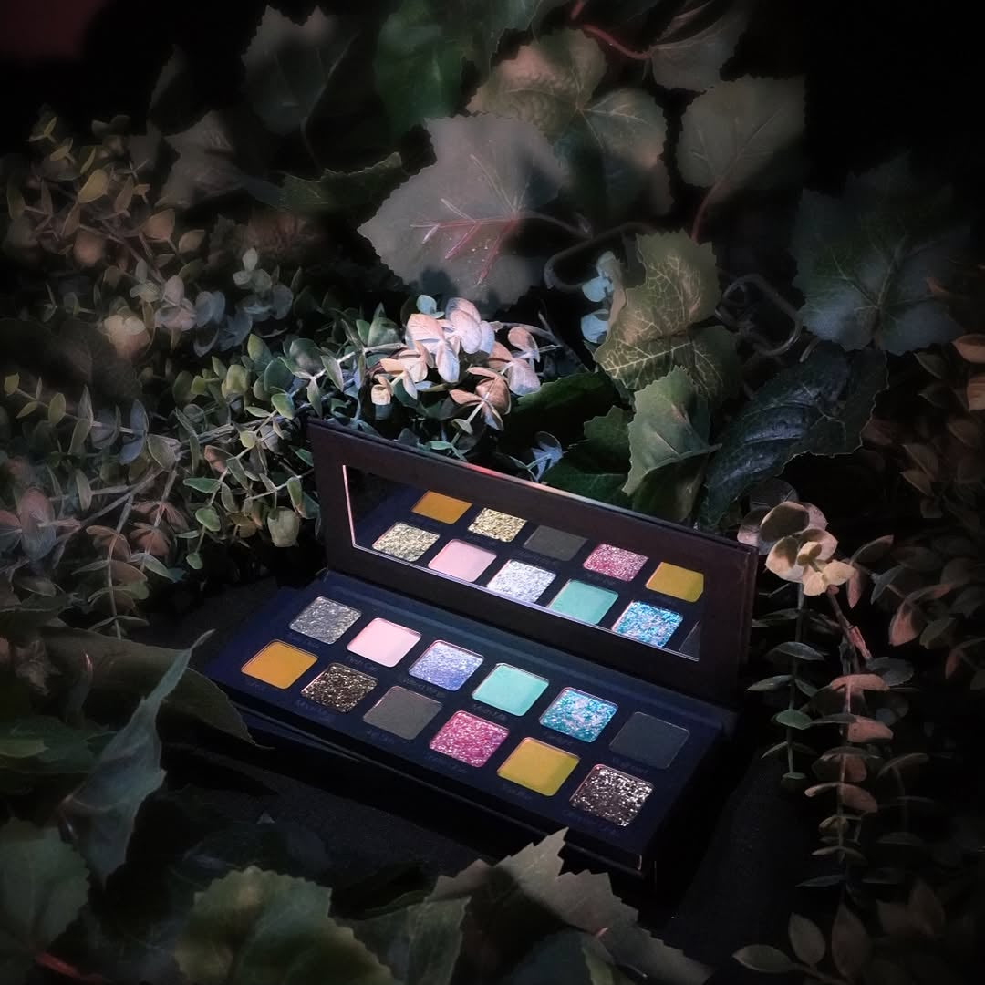 Makeup palette with colorful shades on a dark leafy background