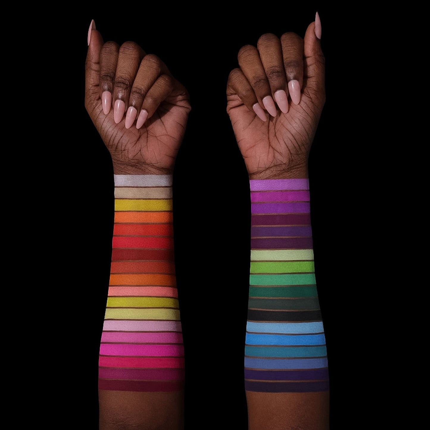 All 36 shades swatched down two forearms on two deep skin tones, full rainbow range from warm reds to cool blues and purples