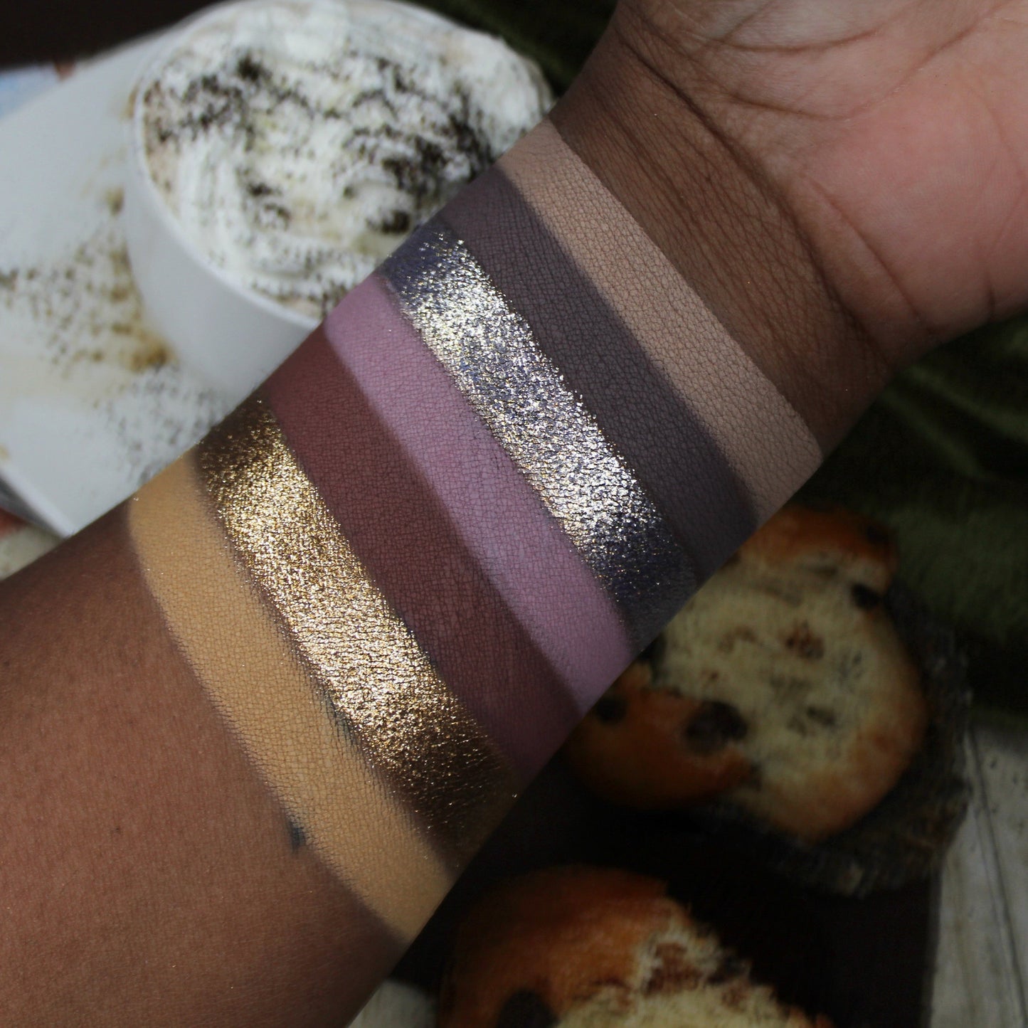 Close-up of a wrist with metallic arm paint swatches against a casual background.