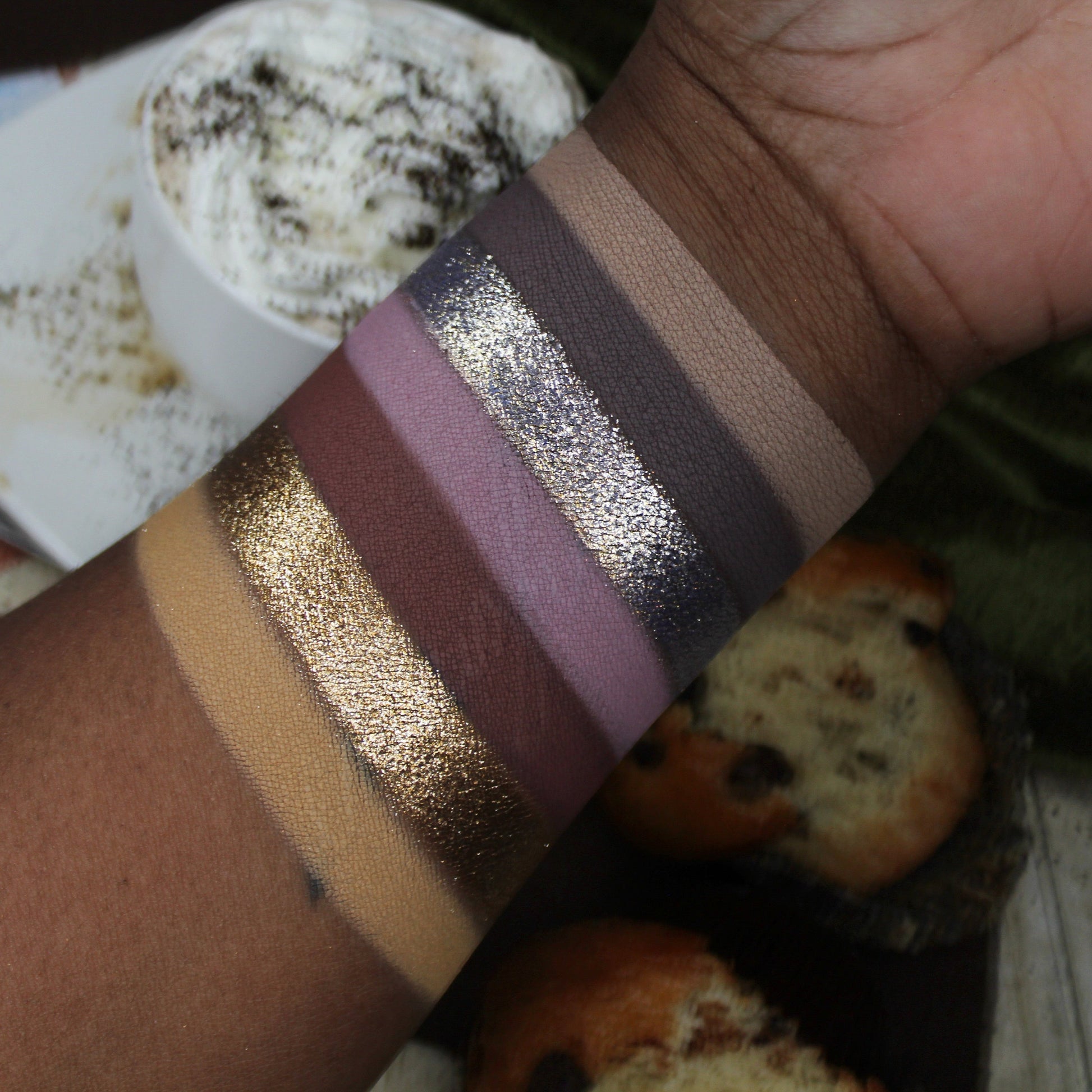 Close-up of a wrist with metallic arm paint swatches against a casual background.