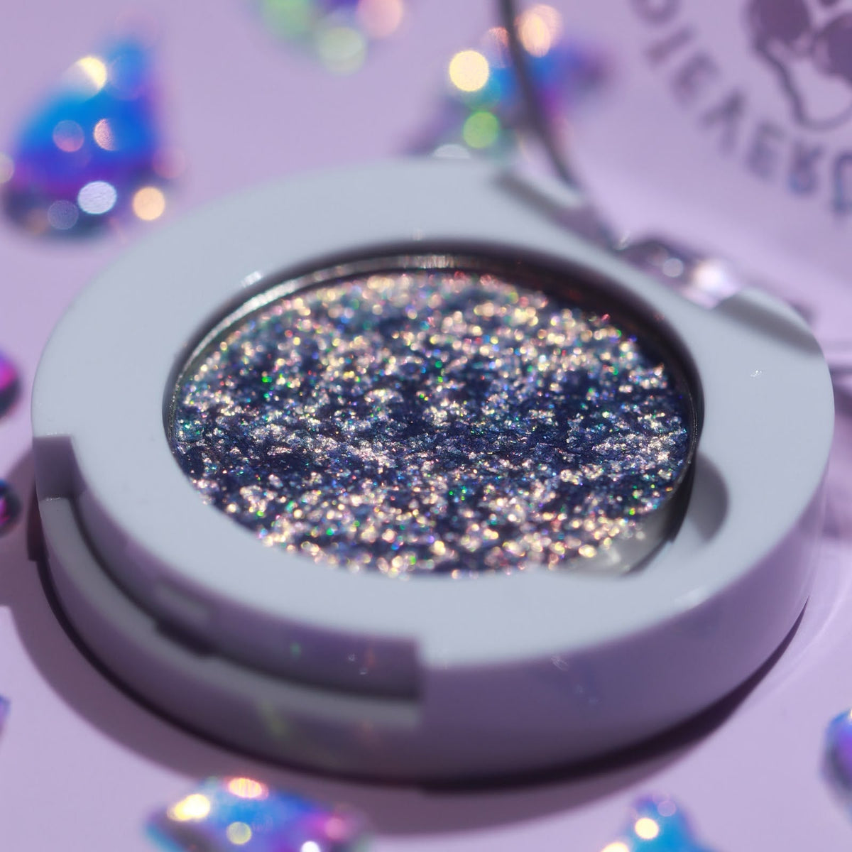 Hexed Holochrome in its open magnetic compact on a lilac backdrop