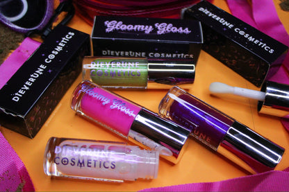 Flatlay of the Gloomy gloss tubes and their printed boxes on an orange and purple backdrop