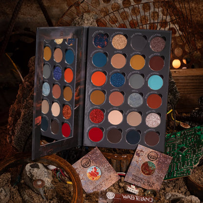 Wasteland palette open on rusted scrap, 24 named pans in rusted reds, burnt oranges, teals and sandy neutrals, with two pressed single pans in front.