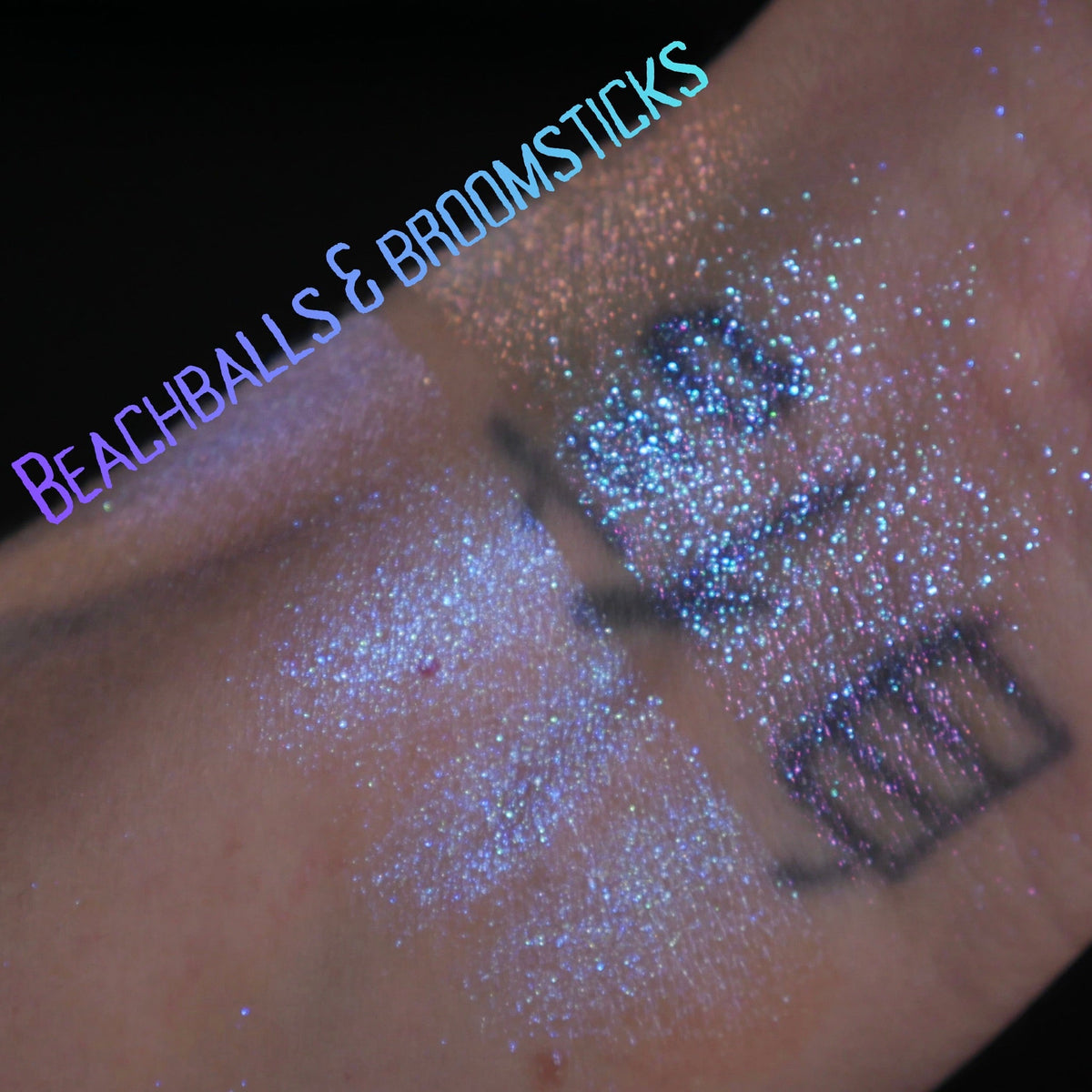 Beachballs and Broomsticks swatched on light skin against black, the lavender side beside the blue sparkle side.