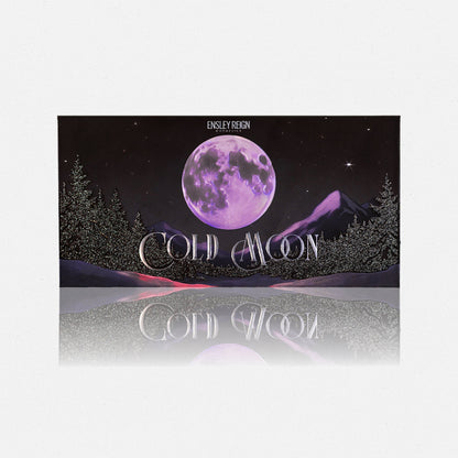 Cold Moon by Ensley Reign Cosmetics - closed packaging with purple full moon over a snowy mountain and pine tree landscape, reflected on grey surface