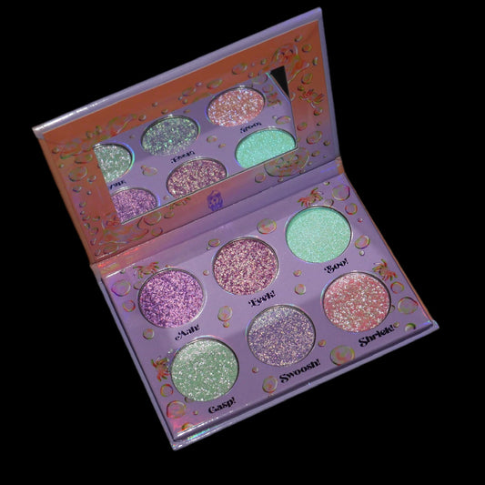 The palette open on a black background, the six labelled pans reflected in the mirrored lid.