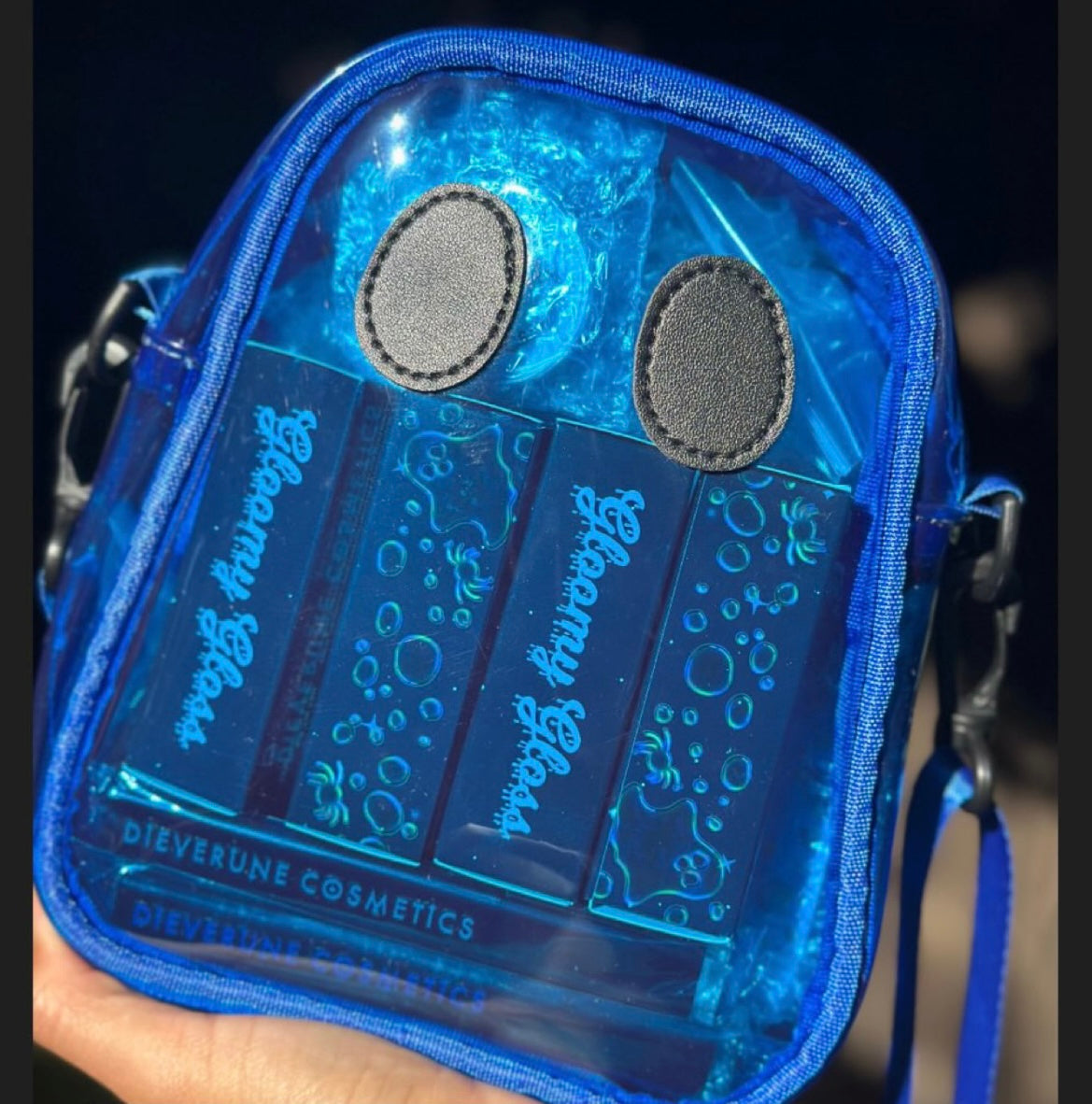 The blue Ghostie bag held up in sunlight with lip gloss tubes inside for scale