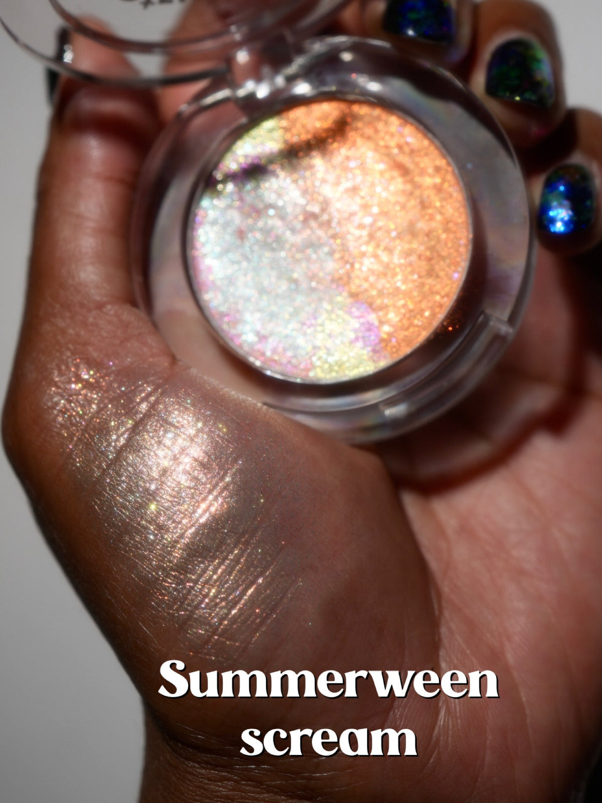 The open Summerween Scream compact held in a palm with a peachy swatch beside it.