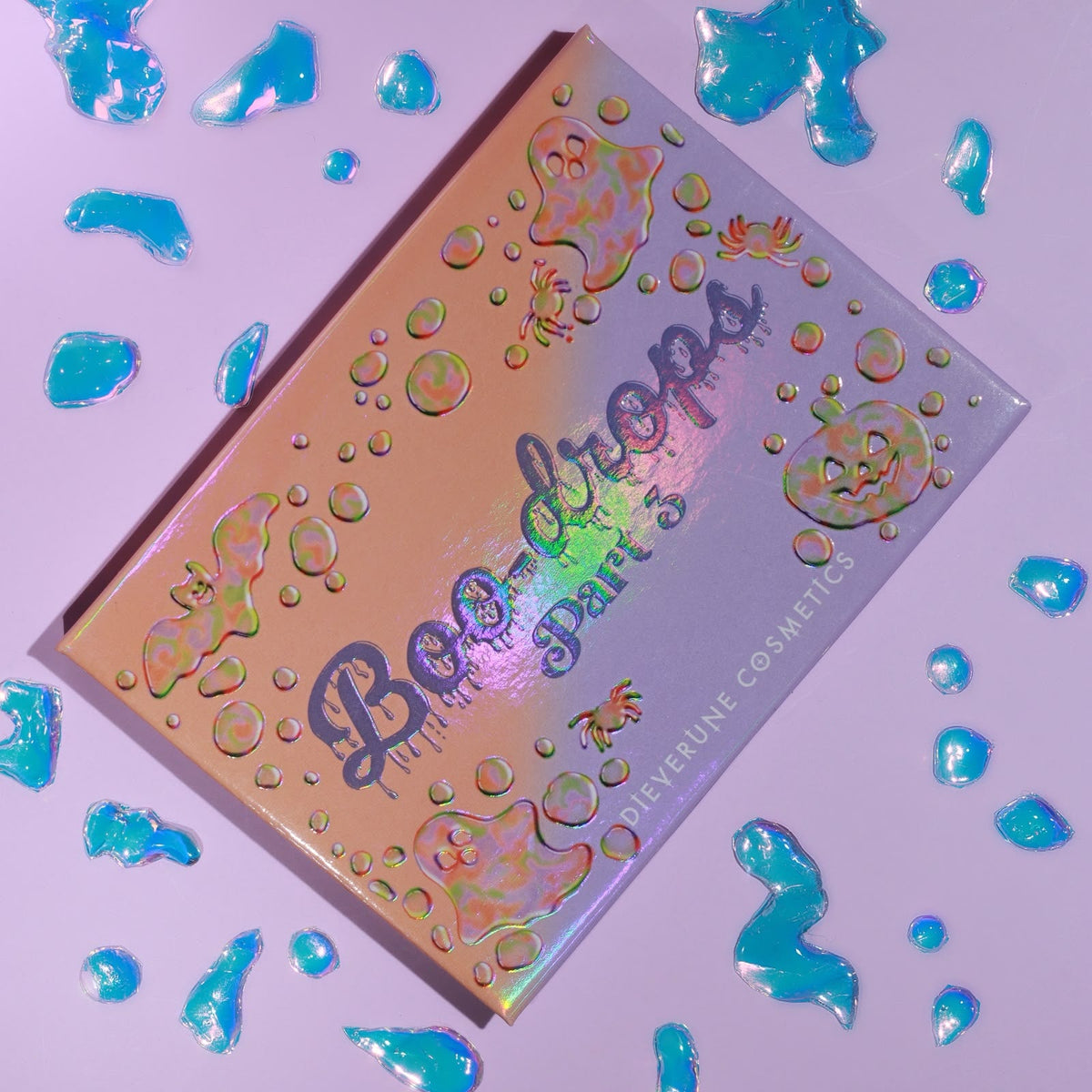 The closed palette on a lilac surface with blue jelly droplets, the holographic lid embossed with ghosts, bats and a pumpkin.