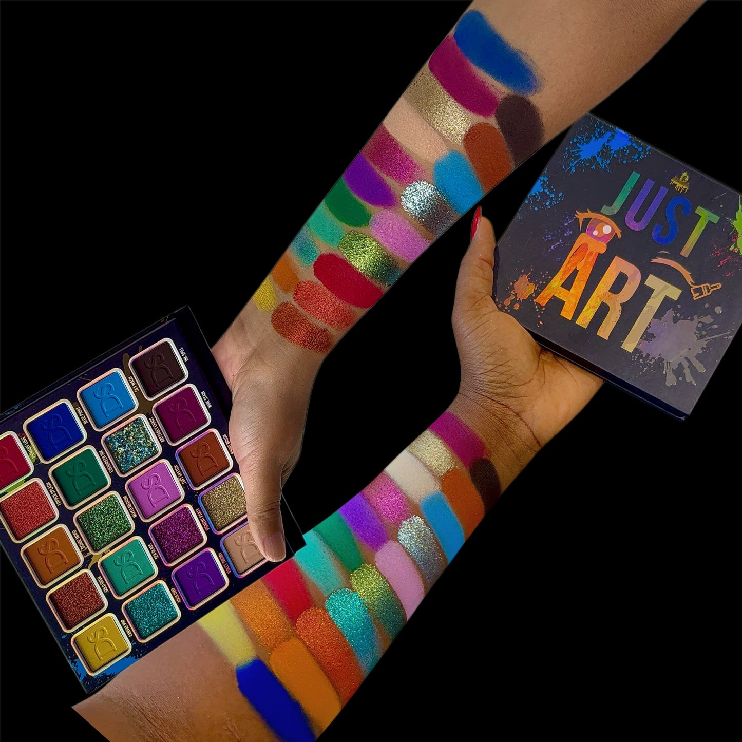 Open Just Art palette held in hand next to arm swatches on two skin tones and the box, black background