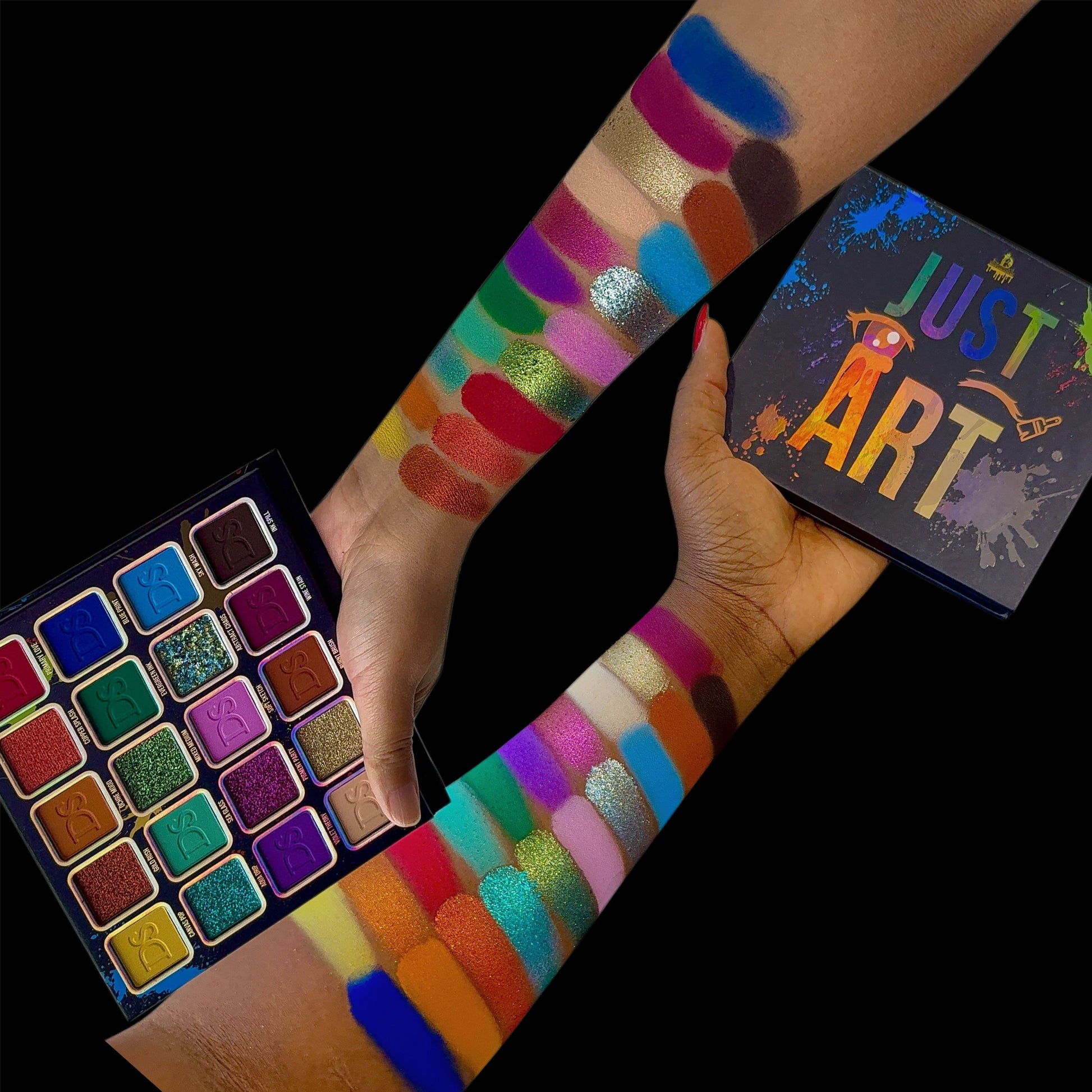 Open Just Art palette held in hand next to arm swatches on two skin tones and the box, black background