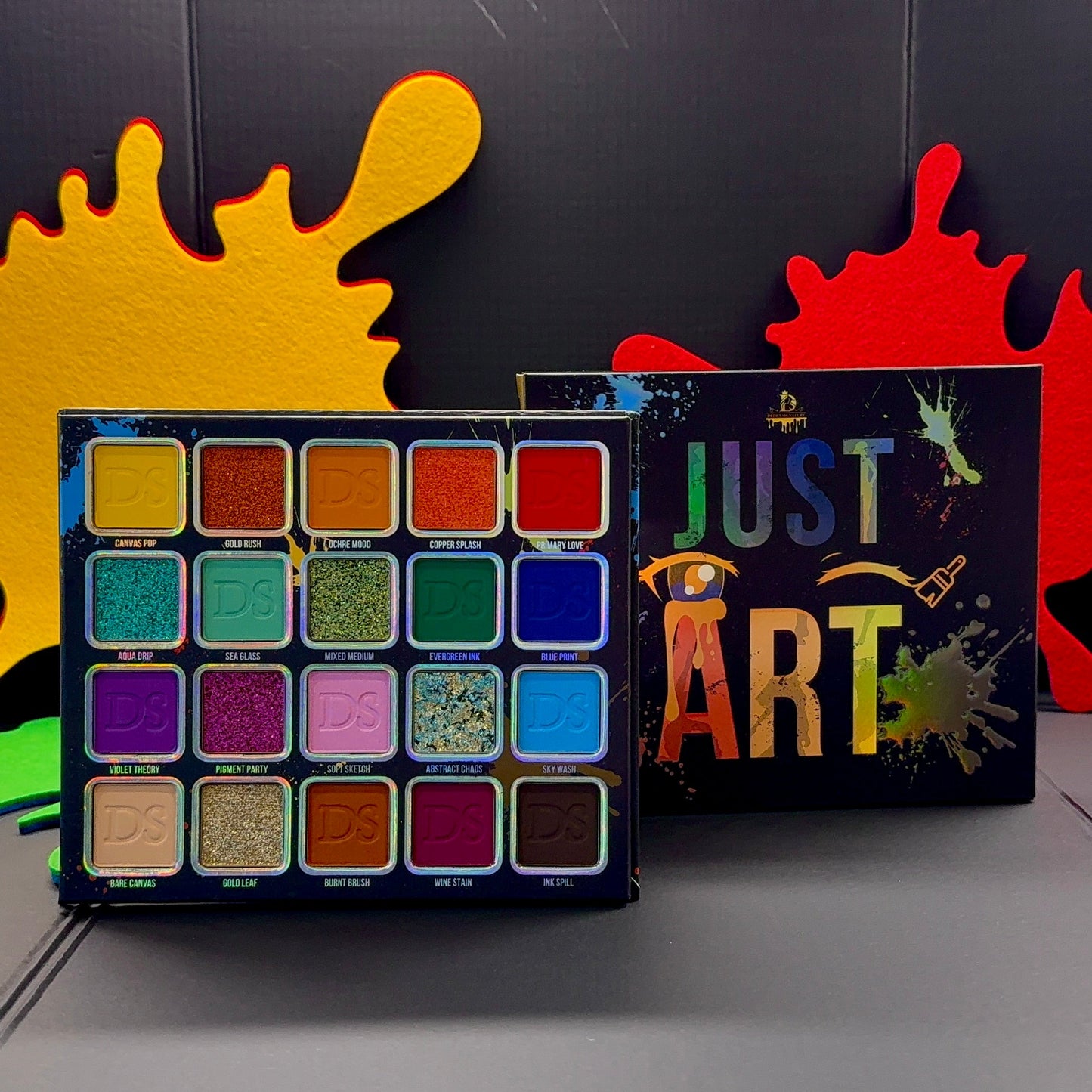 Just Art palette open beside its splatter-art box on a dark backdrop, with the pressed shade grid visible