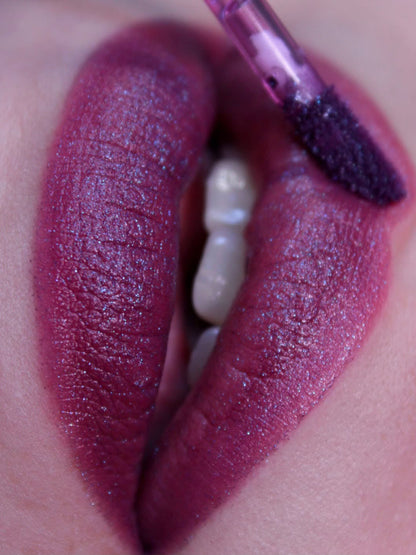 Close-up of lips wearing Pinch, a deep raspberry with a blurred matte finish, applicator at the lip.