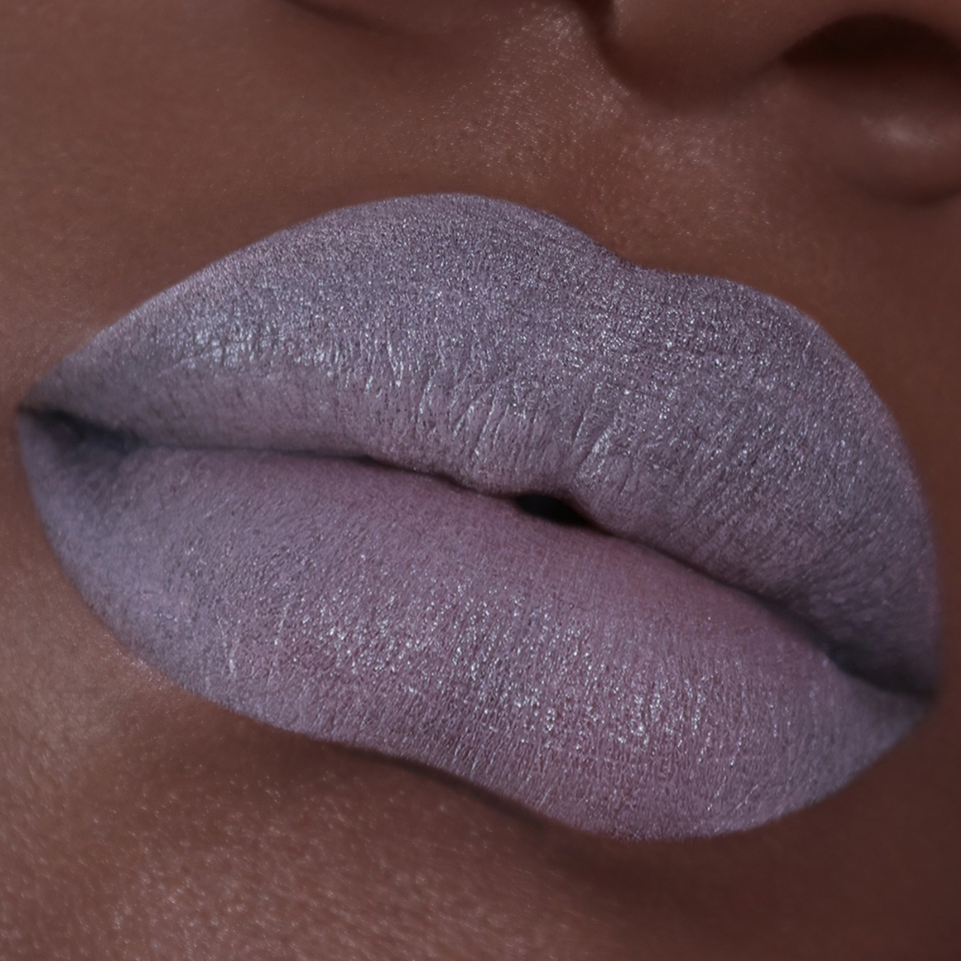 Ghost Milk worn on lips on deeper skin, a cool lilac-grey that reads pale against a warm complexion