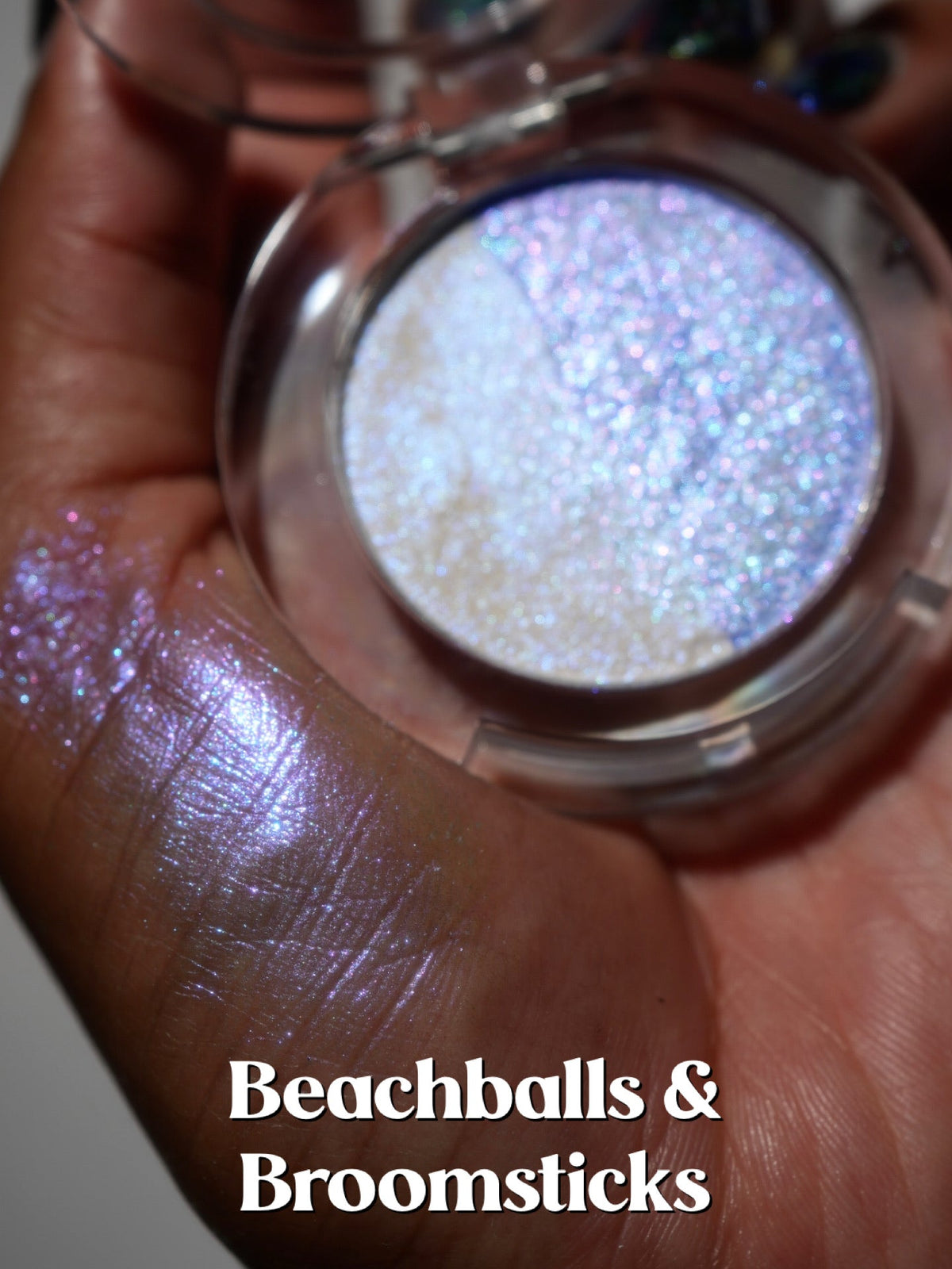 The open Beachballs and Broomsticks compact held in a palm with a swatch beside it.