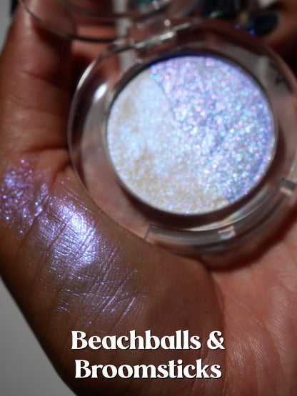 The open Beachballs and Broomsticks compact held in a palm with a swatch beside it.