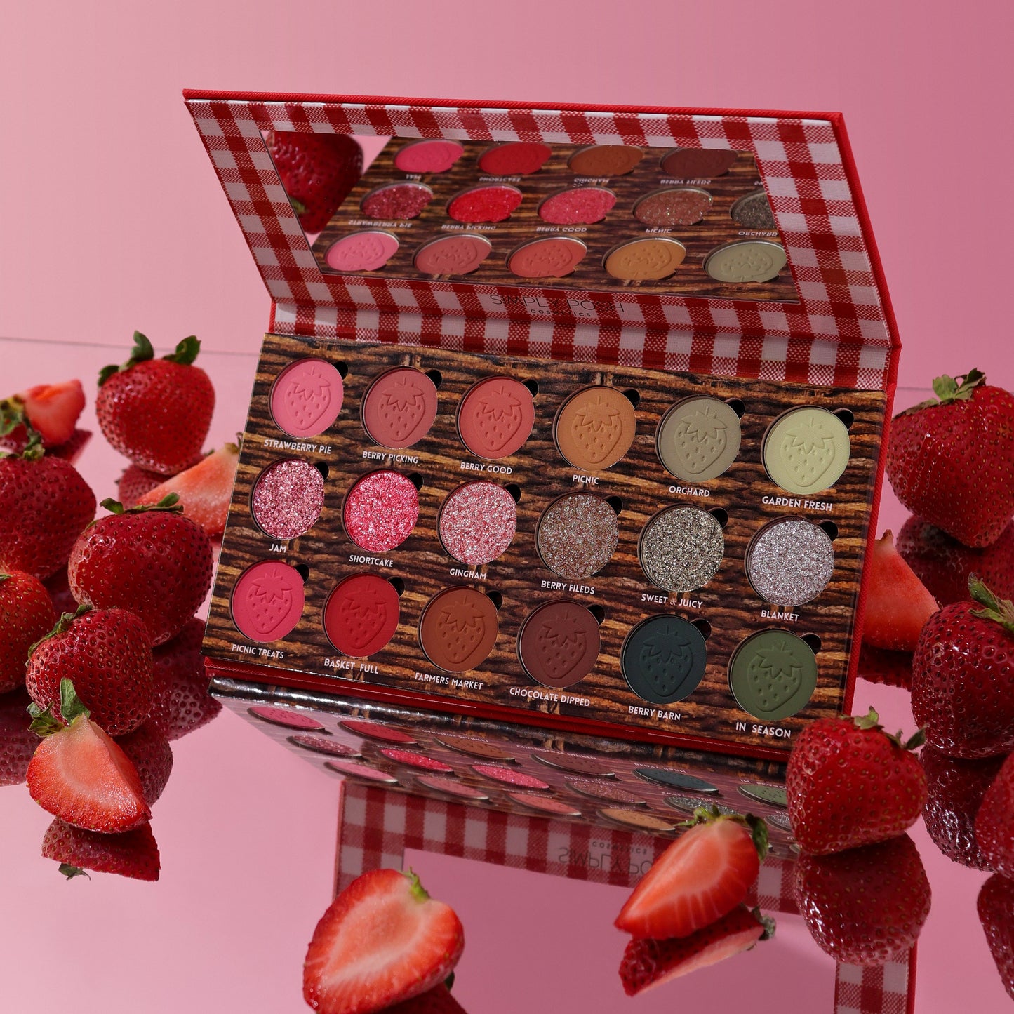 Strawberry Picnic palette open on a pink surface surrounded by fresh strawberries, mirror lid reflecting the pans