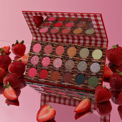 Strawberry Picnic palette open on a pink surface surrounded by fresh strawberries, mirror lid reflecting the pans