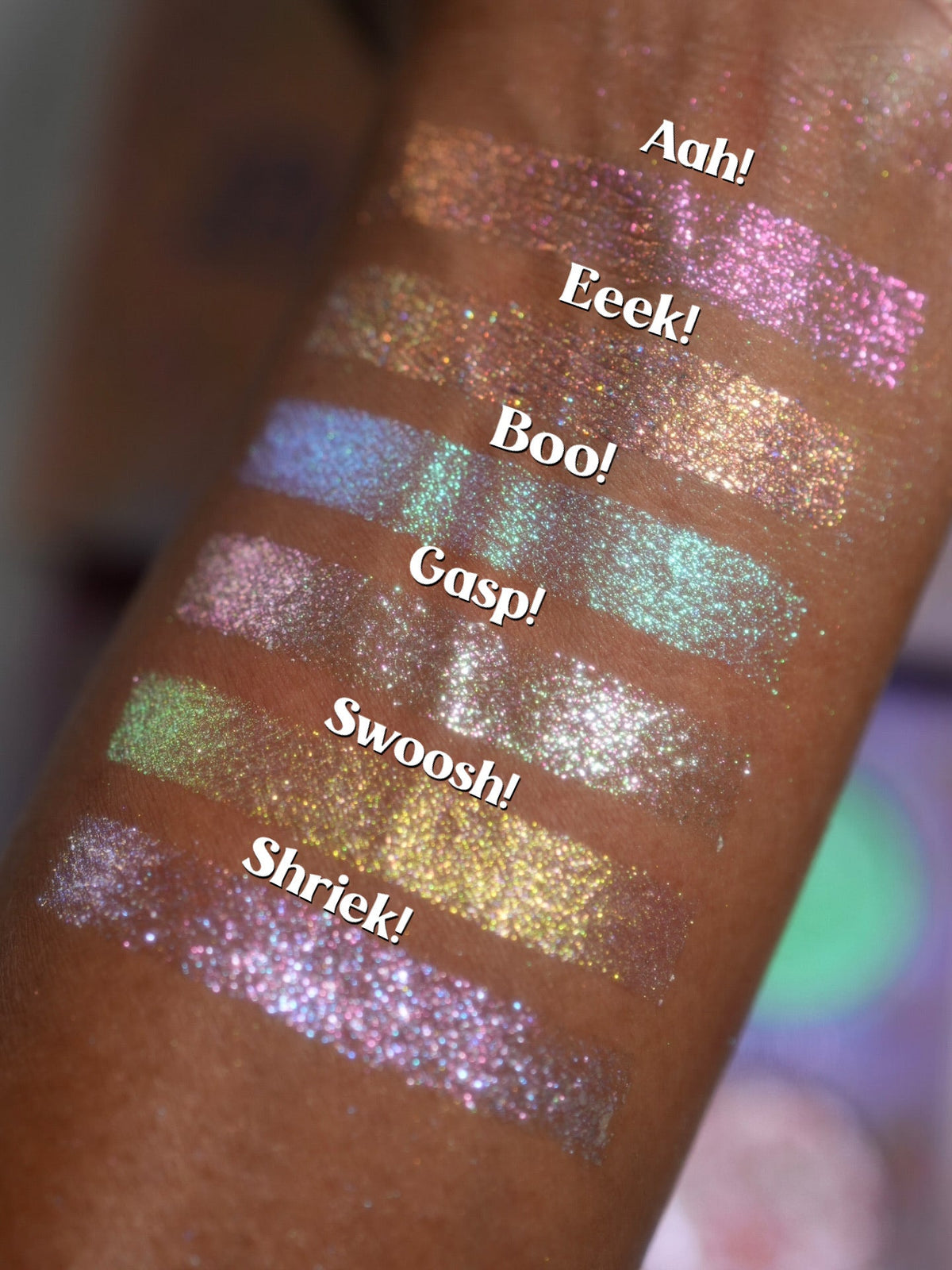 Close-up arm swatches on deep skin, each labelled with its shade name from Aah! down to Shriek!.