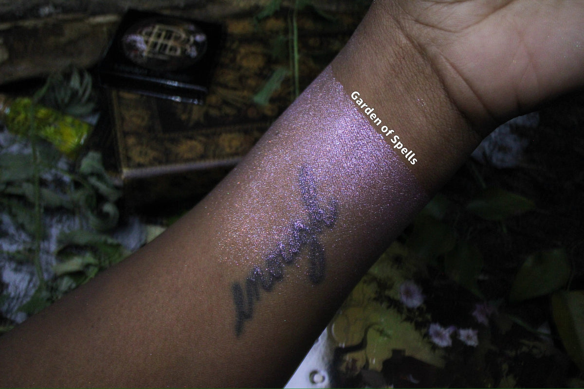 Labelled swatch on deep skin, with the compact and palette cover in frame.