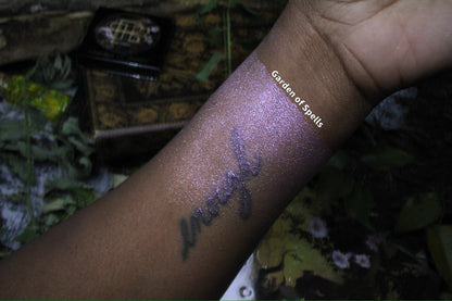 Labelled swatch on deep skin, with the compact and palette cover in frame.
