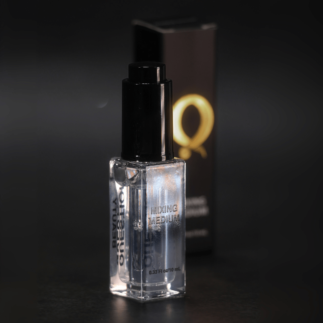 Question Beauty Mixing Medium clear glass bottle with black pump cap, shown beside a dark Q-logo box on a brown surface.