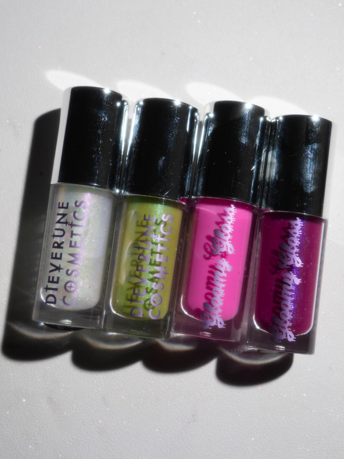 The four Gloomy gloss tubes laid on their sides against a plain grey backdrop