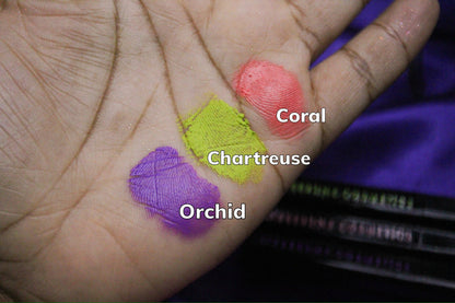 Palm swatches on deep skin, labelled Coral, Chartreuse and Orchid, with the tubes at the right.