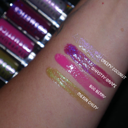 Arm swatches of all four Gloomy glosses beside their tubes, labelled Creepy Coconut, Ghastly Grape, Boo Berry and Melon Choly