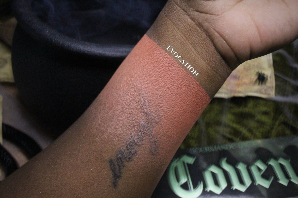 Evocation swatched on deep skin, a warm terracotta stripe labelled with the shade name