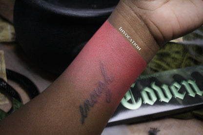 Invocation swatched on deep skin, a rose pink stripe labelled with the shade name