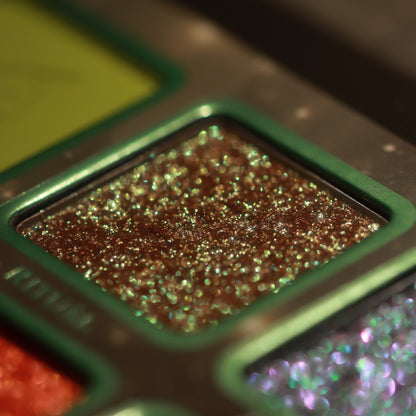 Macro of Ritual, a bronze pan dense with gold and green sparkles